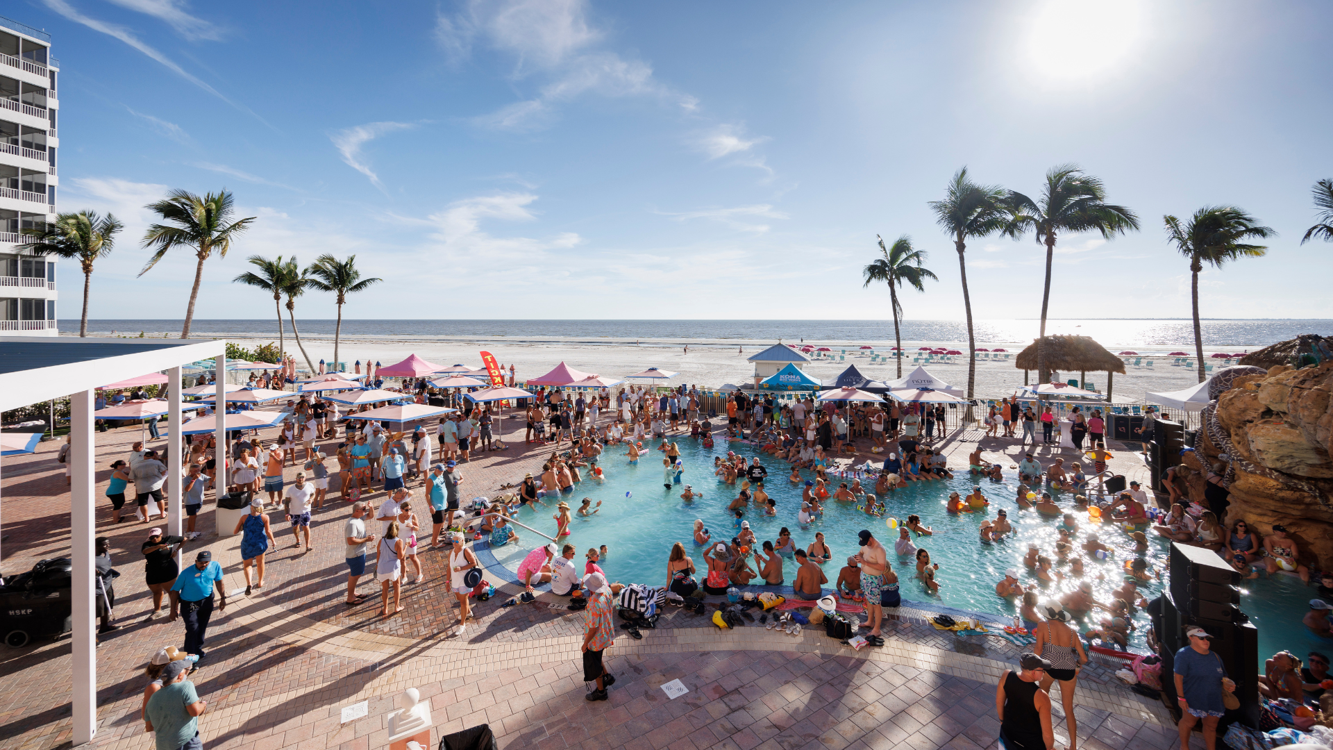 Visitors enjoy the Pink Shell pool party with the pristine Fort Myers Beach just beyond the pool