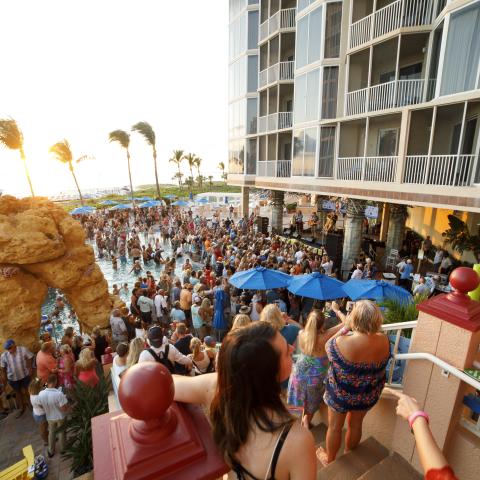 A crowd watches a show at the Pink Shell Beach Resort and Marina at sunset.
